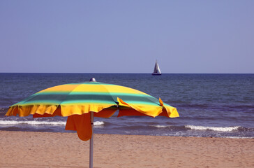 green and yellow colored sun umbrellas on the sandy beach by the sea