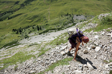 female hiker while walking with backpack on shoulders in the trail in the mountains