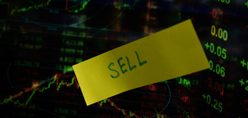 Concept of sell written on sticky notes attached on share market graph.