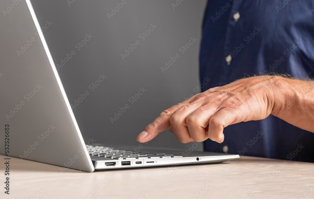 Poster Man forefinger pressing keyboard button at laptop. Male using computer for work, study or leisure while sitting at desk