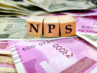 NPS or national pension scheme with wooden bids or blocks on indian rupees notes.