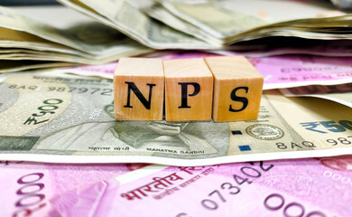 NPS or national pension scheme with wooden bids or blocks on indian rupees notes. - obrazy, fototapety, plakaty