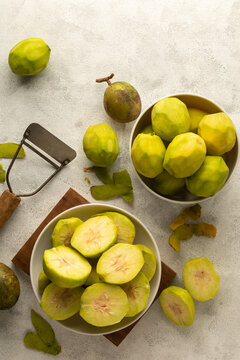 sliced ambarella or june plum on white textured background, cut and peeled edible fruits in a bowl for making vegetarian condiment or sauce, with whole fruits taken from above with copy space