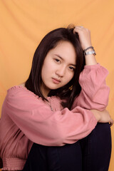 Naklejka premium Young Asian woman wearing a pink crop top. Stand up and take half the body on a yellow background. Express emotions.