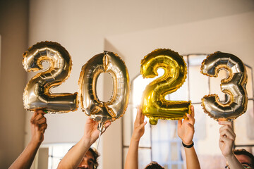 Group of friends at a party celebrate happy new 2023 year with elegant inflatable gold text - People have fun together at home - 532527859
