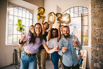 Group of friends at a party celebrate happy new 2023 year with elegant inflatable gold text -...