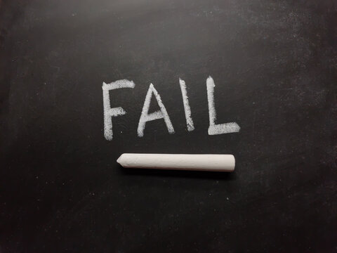 Fail word written on blackboard or slate with chalk.