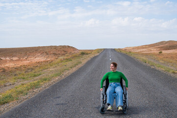 Woman in a wheelchair on a highway in the steppes. 
