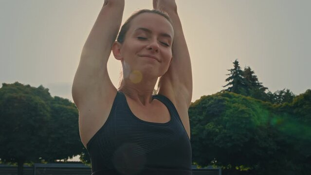 Caucasian athletic woman runner stretching body warm up before workout preparing for outdoor jog girl wearing sportswear raising arms morning breath exercises outside for health wellbeing energy life