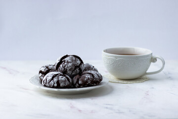 Cookies chocolate cracks on a white marble table. Biscuits and a cup of tea