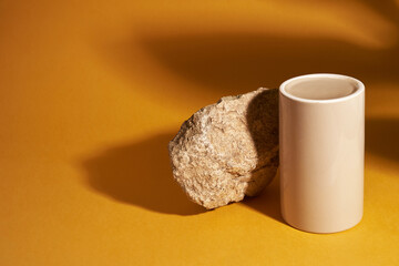 A pedestal made of porcelain for the presentation of the product against a background of stone and the shadow of a plant. A design element with space to copy. High quality photo