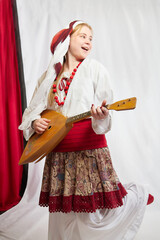 Beautiful smiling girl in stylized slavic red and white national costume and balalaika on white...