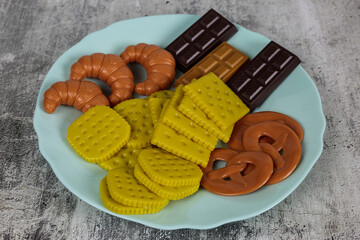 Game for children with products. Plastic food mockup. Artificial food in a bowl. Fake food in a blue plate on a white background
