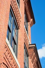 Decorative red brick cornice on 19th century textile mill building set against bright blue sky