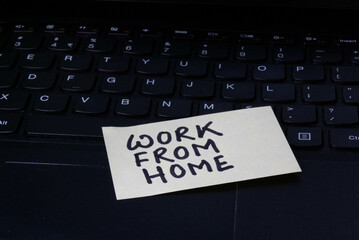Work from home written on sticky note attached on laptop.
