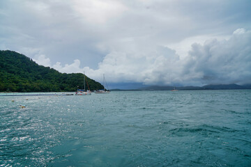 Boats in the Andaman Sea have an island backdrop on an overcast day.