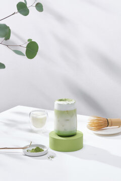 Matcha latte with milk foam in tall glass on light background