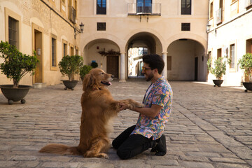 young latino man with sunglasses and beard and his brown golden retriever dog look at each other with love and affection. Concept pets, animals, dogs, love to retriever pets.