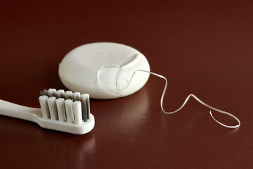 Dental floss and toothbrush on a brown background. Dental care.