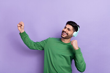 Photo of good mood cheerful guy green long sleeve headphones singing favorite artist dancing fists up isolated on violet color background