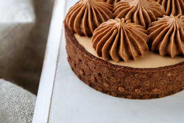 Mini chocolate cakes on wooden background. Chocolate cream rosettes on a cake.