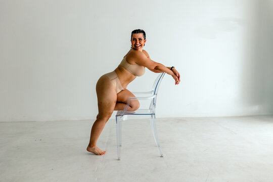 Curvy woman poses with clear chair
