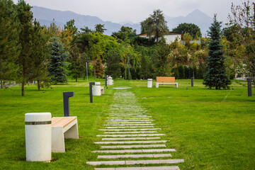 a bench with an urn on green grass near a rocky path