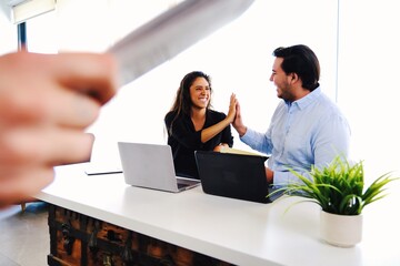 Successful young businessperson celebrating giving high five in modern office