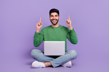 Full length photo of young hispanic man sit lotus pose point up empty space dressed trendy green outfit isolated on violet color background