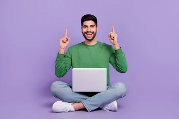 Poster Full length photo of young hispanic man sit lotus pose point up empty space dressed trendy green outfit isolated on violet color background © deagreez