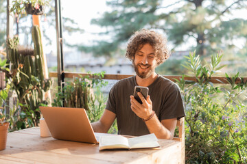 Man working with laptop on the terrace receive a text message 