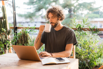 Man working with laptop on the terrace and drinking coffee 