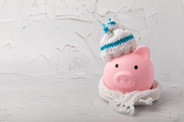 Savings concept. Piggy bank and money on a yellow textural background. A piggy bank in a warm winter hat that saves heat. The concept of saving heating. Place for text. copy space