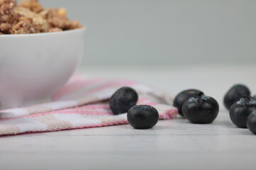 a bowl of granola and blueberry on a napkin on wooden background