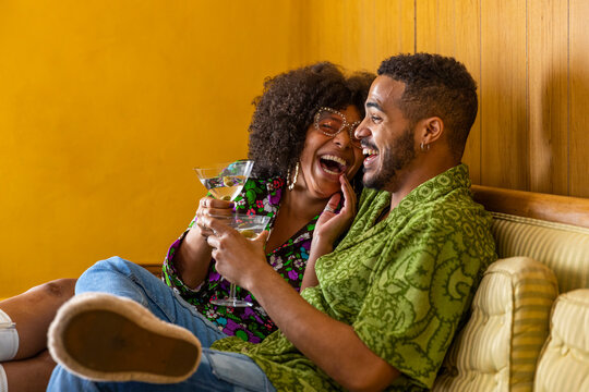 Black Couple laughing enjoying martini on couch living room 
