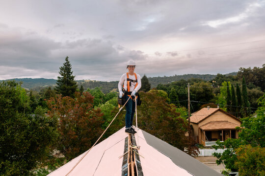 Woman on top of roof holding security harness
