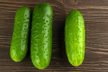Three cucumbers in close-up on a wooden background.