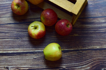 Group of apples inside a wooden box and outside on rustic background. Aerial view.
