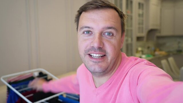 Millennial henpecked male househusband makes a selfie, video call to his wife and says that he hung all the wet laundry on the dryer as she asked