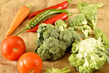 Ripe vegetables, broccoli, chili peppers, tomatoes and table carrots on a white table.