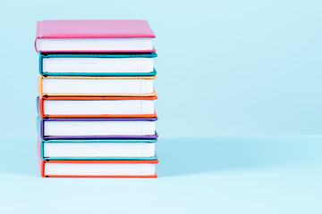 Stack of books on light blue background. Front view, copy space fot text or product. Education, back to school concept