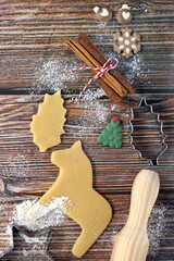 Baking figures cut out of dough bakeware and other kitchen items for baking Christmas cookies are on a wooden background. Copy space. View from the top point.