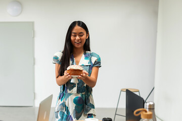 Asian woman holding cake at work