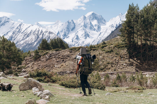 Backpacker walking in valley near mountains