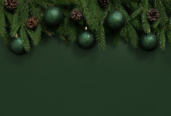 Christmas border with fir branches, cones and baubles on green background. Christmas dark green background. New Year. Greeting card. Copy space, top view, flat lay.