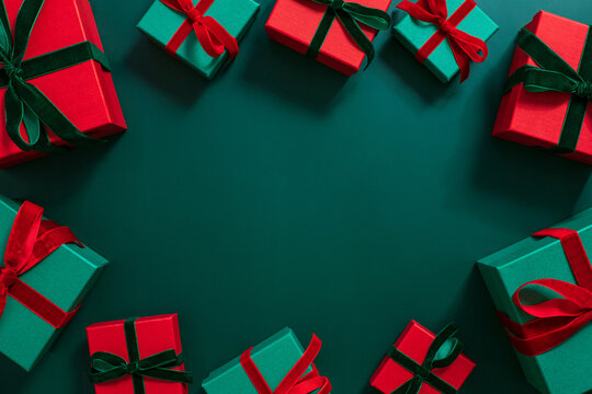 Gifts frame on a green background. Christmas or festive decorations. Green and red gift boxes. Copy space, top view, flat lay.
