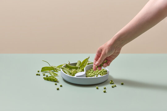 Silicone plate filled with green peas by woman.