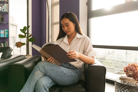 Asian woman reading book at home
