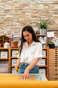 Asian woman cutting fabric in small business