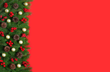 Christmas red background with fir branches, cones, berries and golden baubles. Christmas border. Festive greeting card with space for text. Top view, flat lay.